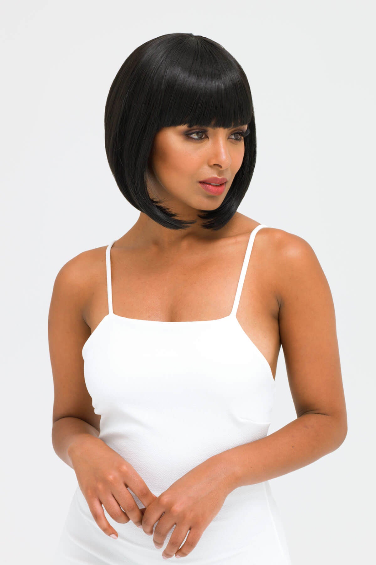 Woman wearing a white dress with a plain background. Black inverted bob wig: Chloe