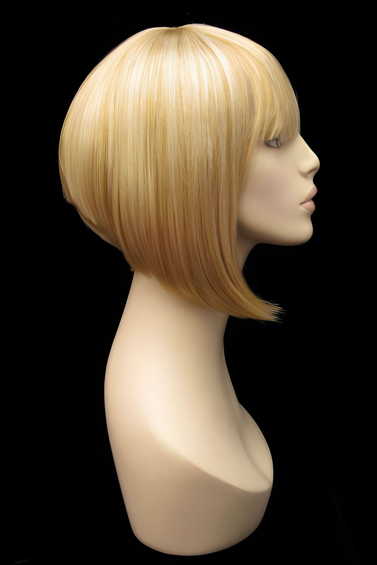 Blonde wig on a mannequin head against a black background. Blonde inverted bob wig: Rhiannon honey blonde 24BH613