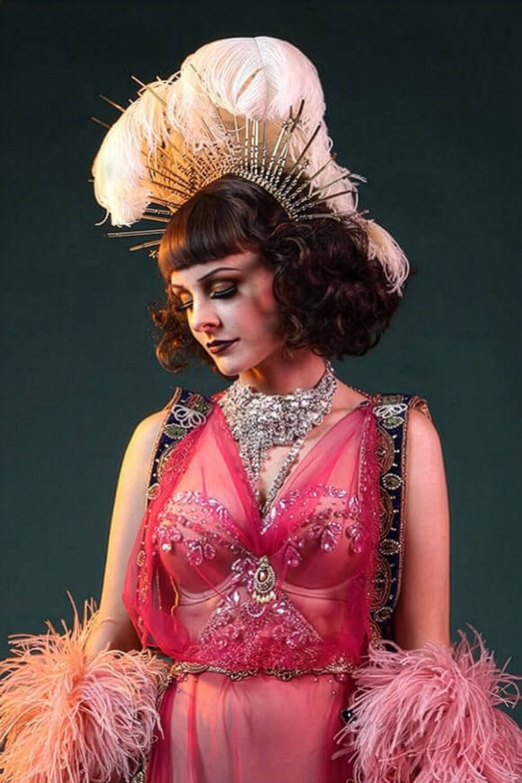 Person in a vintage-style pink dress with feathered headpiece against a dark background. A short brown vintage style wig with waves: Rita brown 8