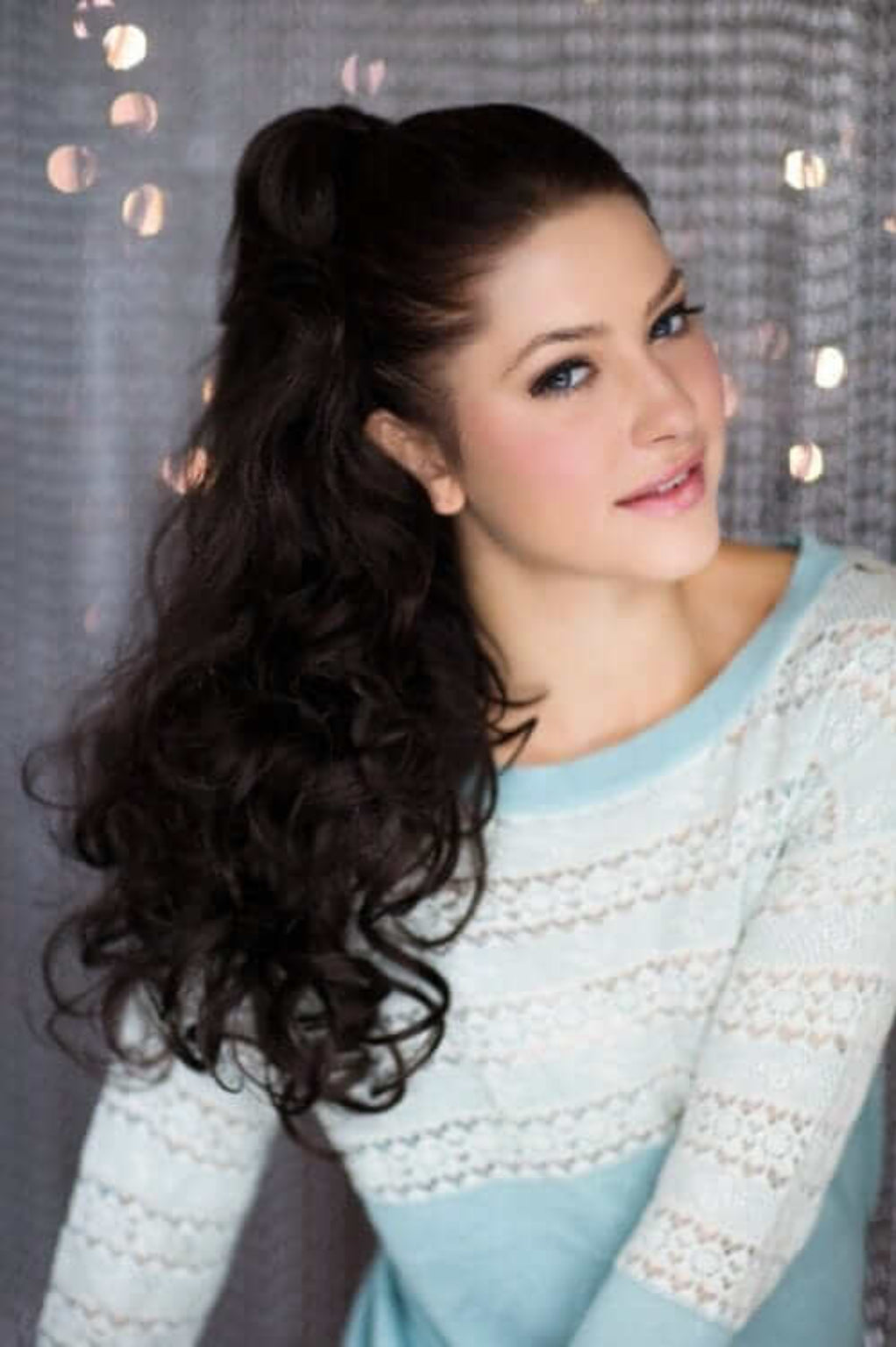 A woman wearing a long wavy ponytail hairpiece extension with loose and layered curls. Long wavy ponytail hairpiece extension: Tiffany