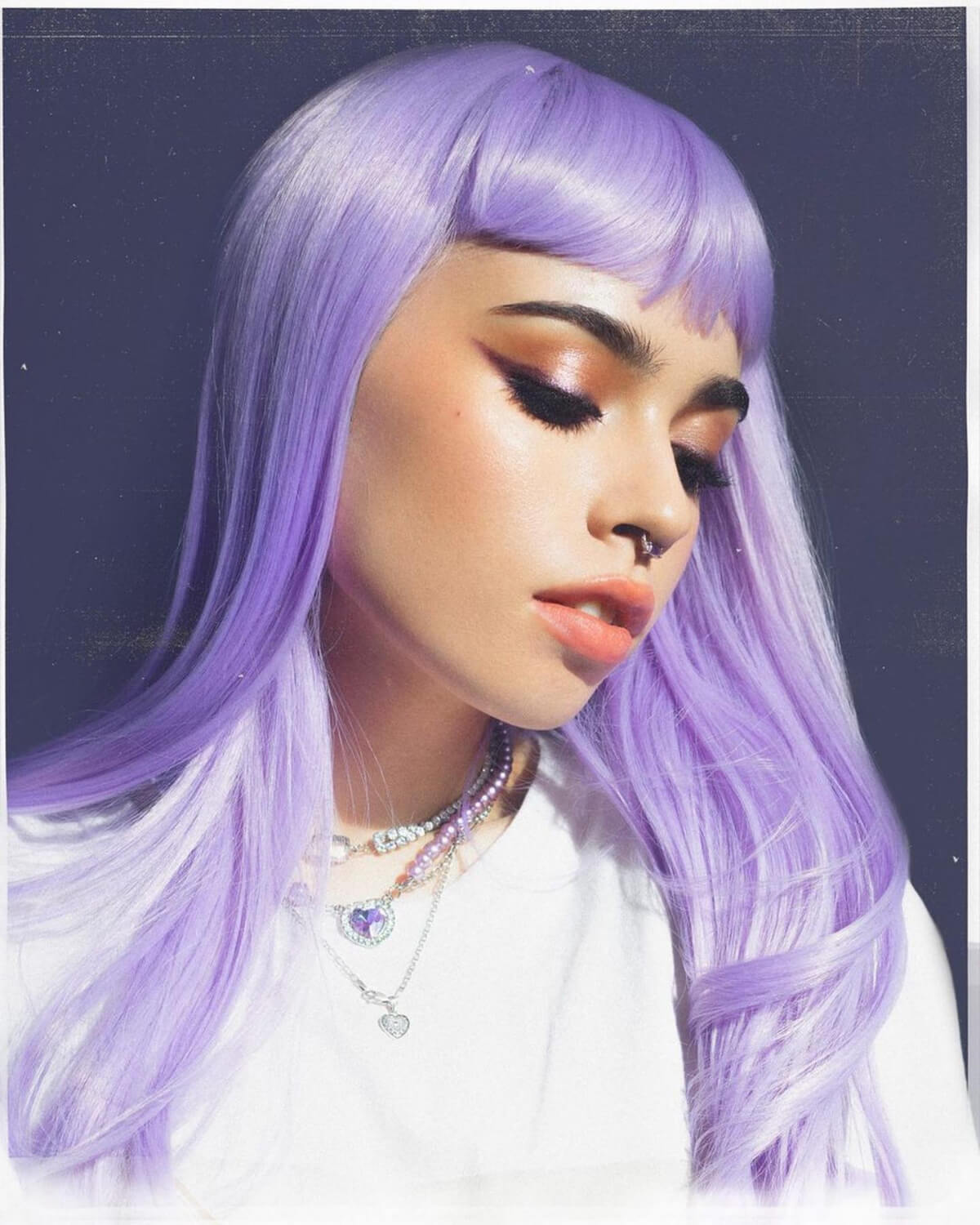Person with long purple hair wearing a white shirt against a dark background. Long, Pink-Purple Wig With Short, Straight Fringe: Seraphina