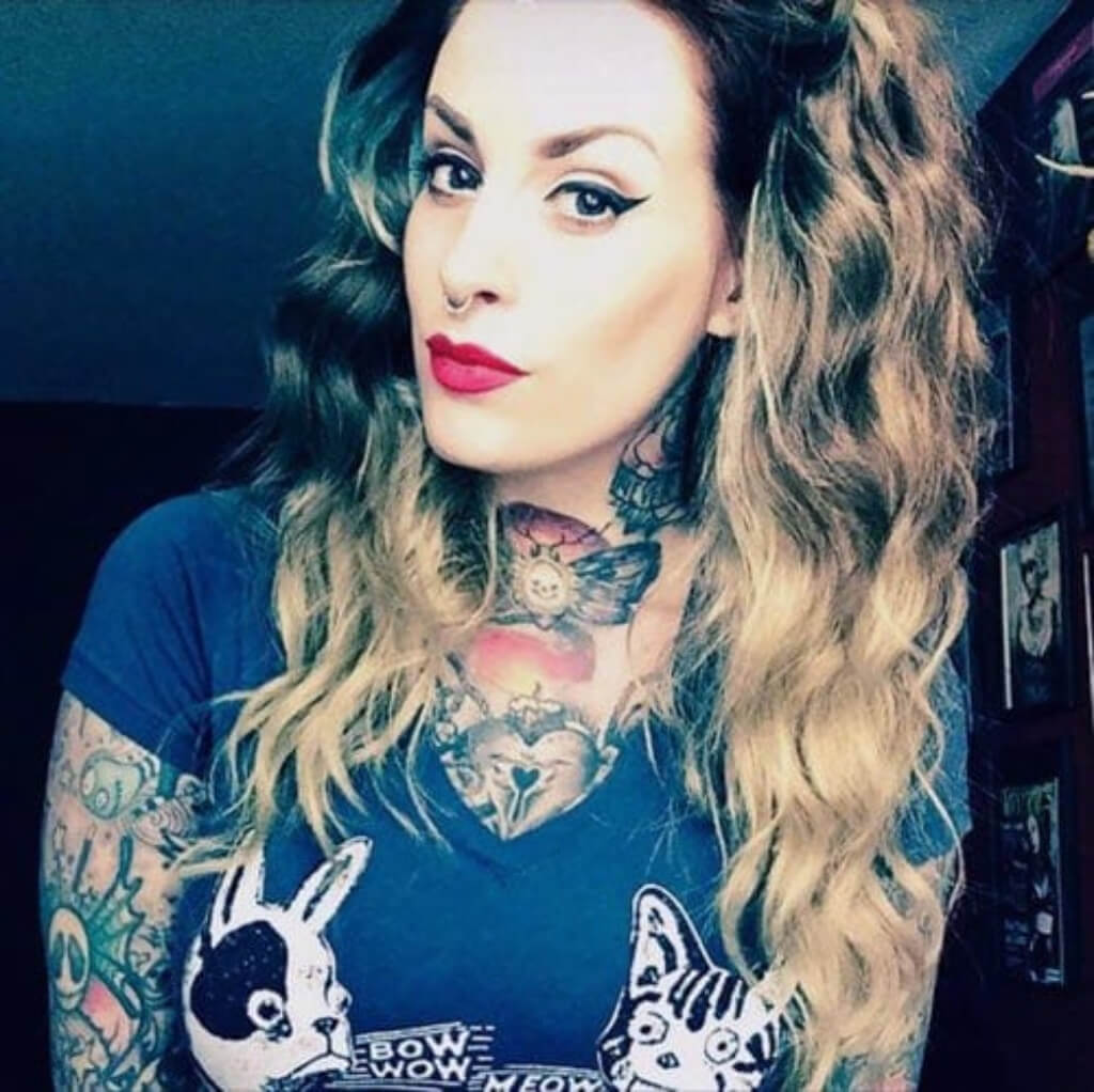 Woman with tattoos wearing a blue t-shirt with cat designs. Dip dye chocolate brown and honey blonde wig long wavy wig with no fringe: Genevieve