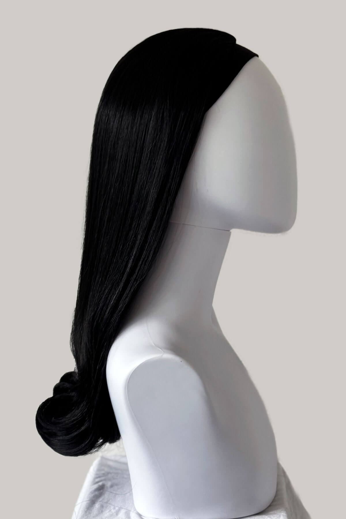 Black wig on a mannequin head against a plain background. 1960s Retro high crown, half wig hairpiece, long with hair flip: Priscilla black 1b