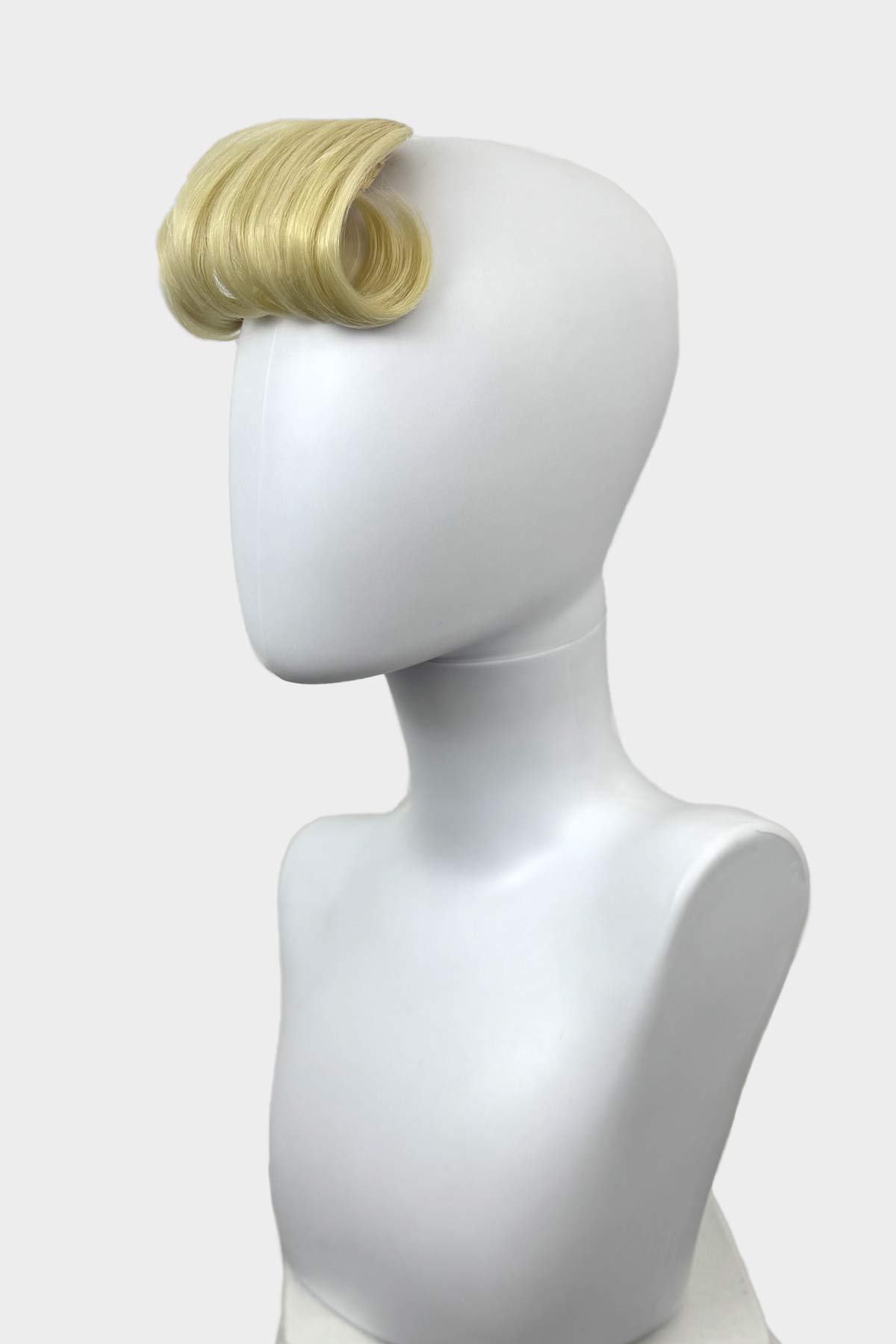 Blonde hair extension on a white mannequin head against a white background. Victory roll fringe/bangs hairpiece, 1950s vintage style: Rosa light blonde 613