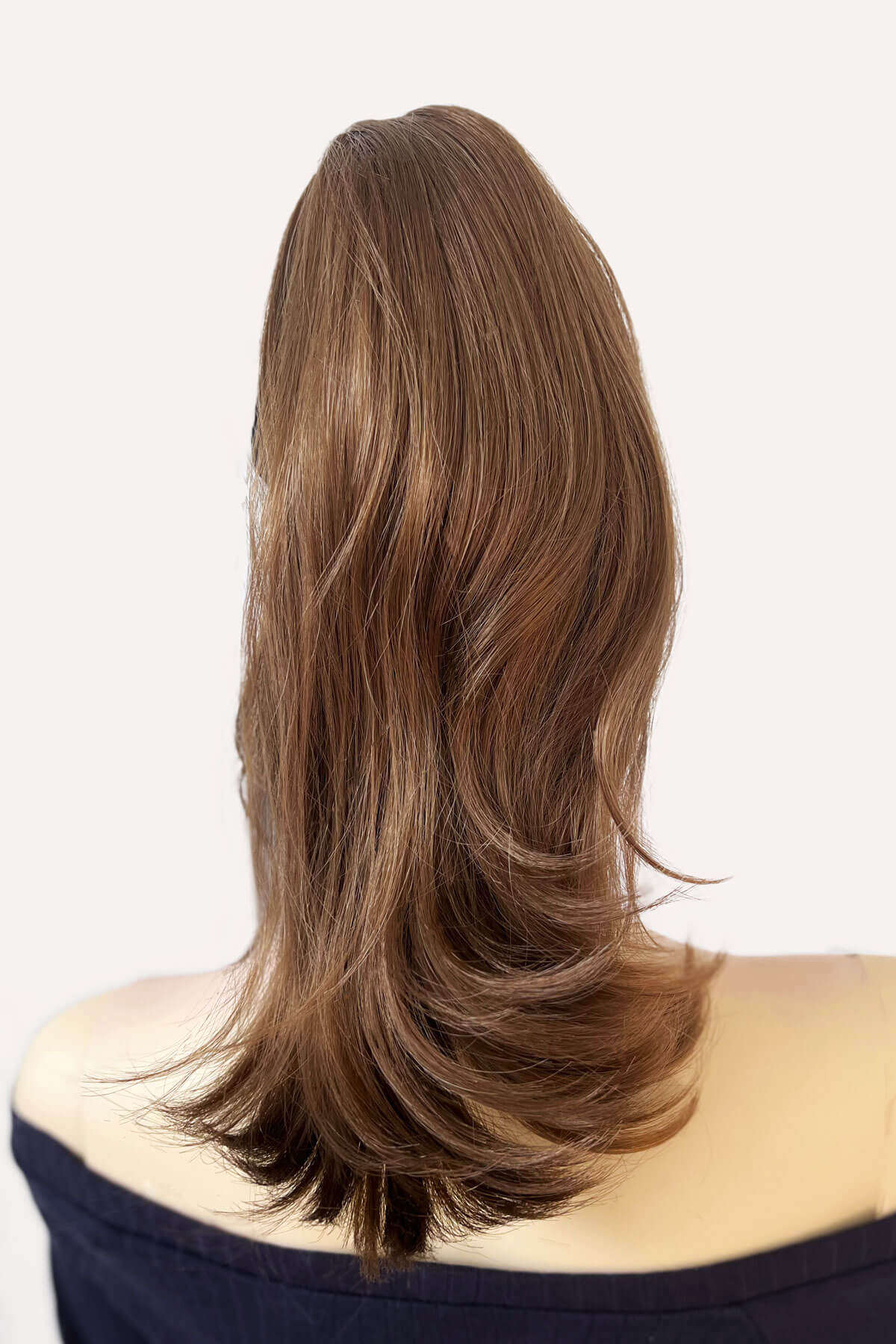 Back view. Mannequin head with brown hair styled in a ponytail wearing a black headband on a beige background. brown 12