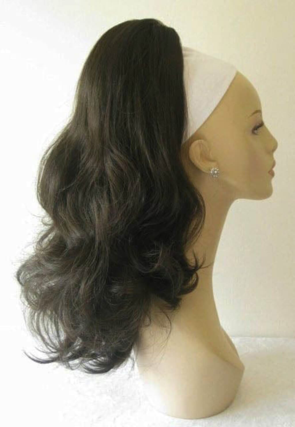 Black wig on a mannequin head with a white background. Ponytail hairpiece extension, layered with waves: Elsa dark brown 4