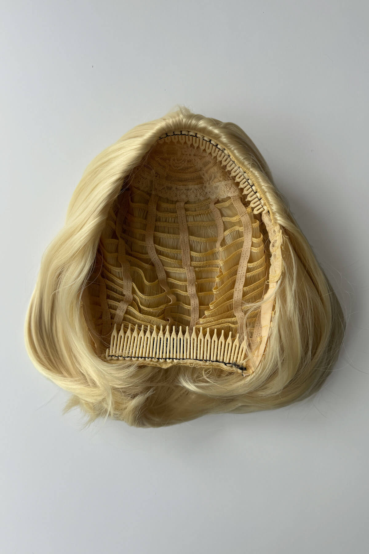 Blonde half wig with a comb on a grey background.  Bob half wig hairpiece, heat styleable - Amelie blonde 613