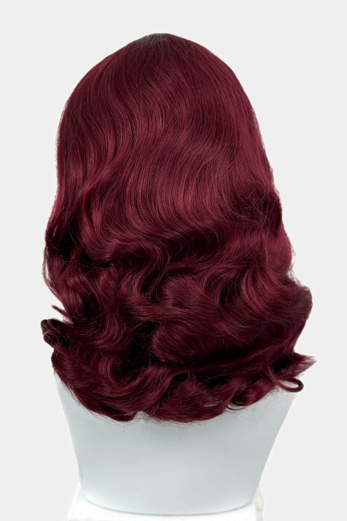 Red wig on a white mannequin head against a white background viewed from the back. 1950s style shoulder length half wig hairpiece with beautiful vintage waves: Onyx cherry red 39 