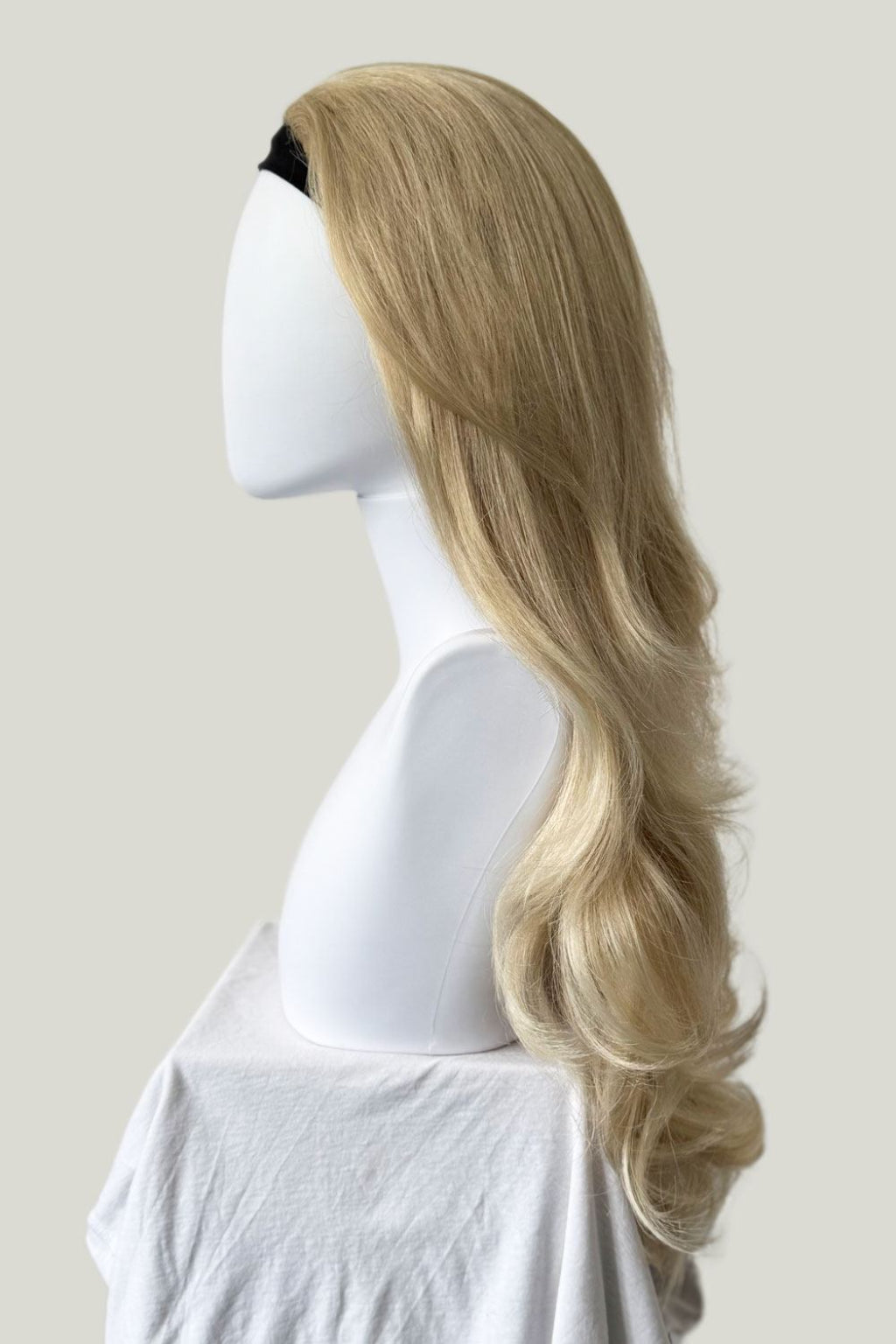 Blonde wig on a mannequin head against a plain background. Blonde half wig hairpiece (3/4 wig), loose curls: Suki blonde 613T24