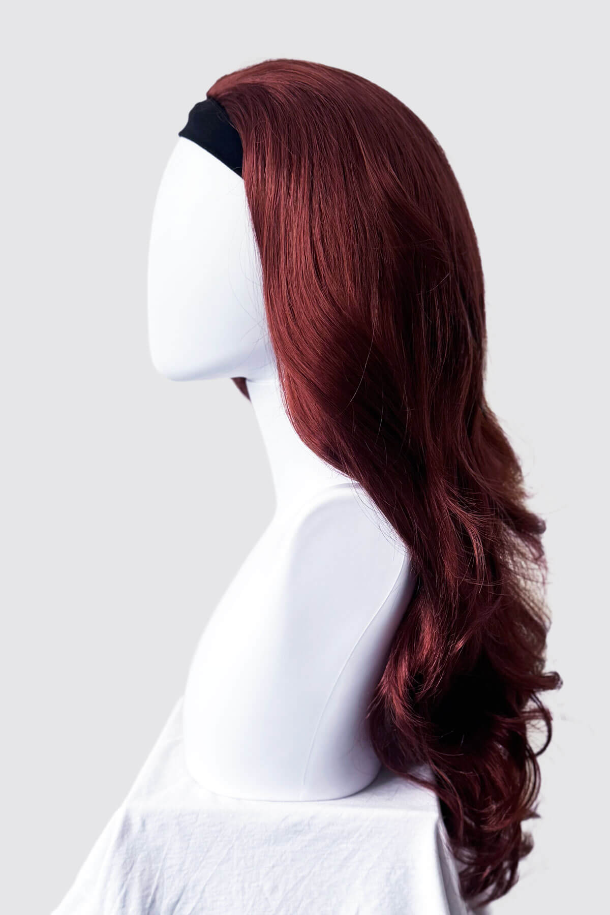 Red wig on a mannequin head against a white background. Red half wig (3/4 hairpiece) with long waves: Sasha copper red 130