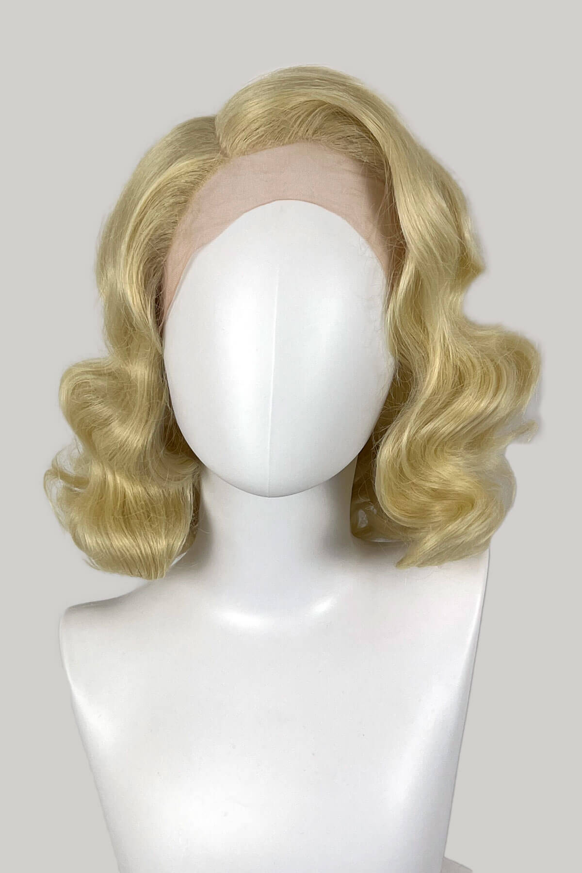 Blonde wig on a mannequin head against a white background. Blonde lace front wig, pinup/vintage style, mid length with finger waves: Lucinda