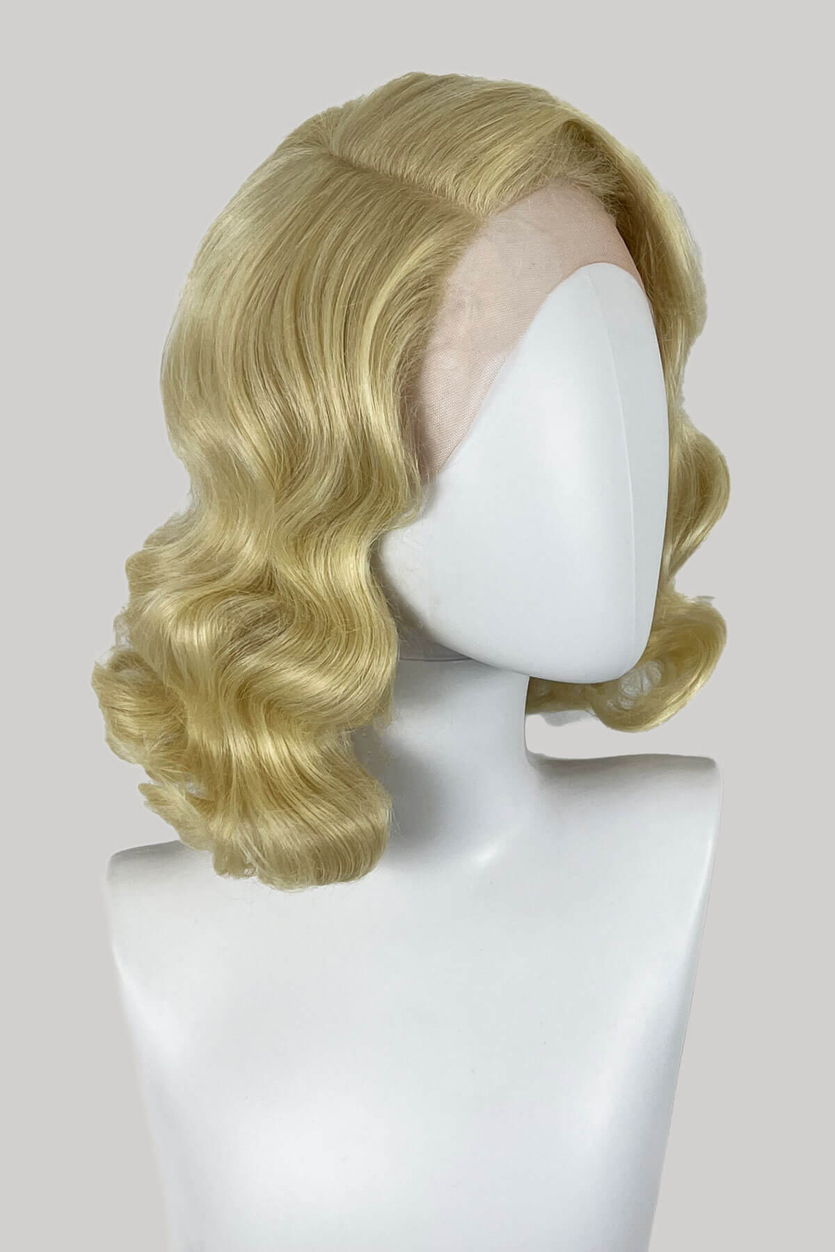 Blonde wig on a mannequin head against a plain background. Blonde lace front wig, pinup/vintage style, mid length with finger waves: Lucinda