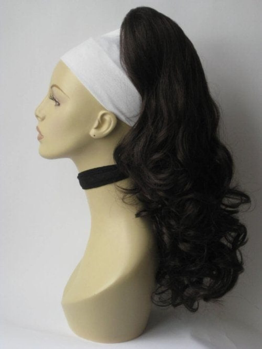 Mannequin head with dark brown wavy hair styled in a ponytail and white headband on a white background.Long wavy ponytail hairpiece extension: Tiffany dark brown 6