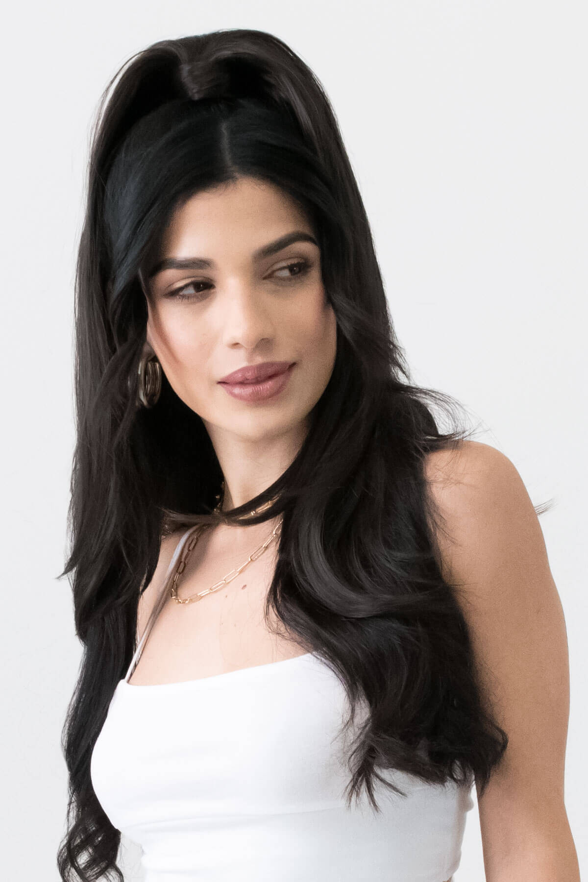 Woman with long black hair styled in a high ponytail against a white background. Long sleek ponytail extension with gentle, layered waves: Mali dark brown 4