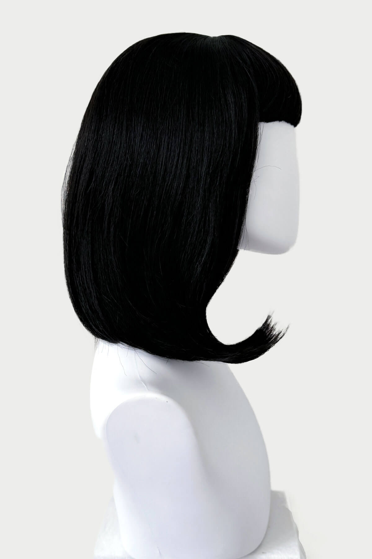 Black wig on a mannequin head against a white background. Black long bob wig with a short retro, rockabilly-style fringe: Beth