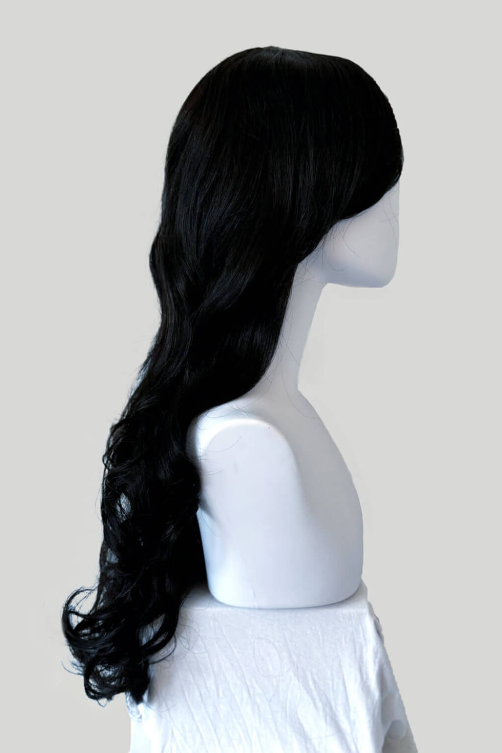 A long, wavy black wig displayed on a white mannequin head and shoulders against a light grey background. Long wavy black wig with side-sweeping Fringe: Charlotte
