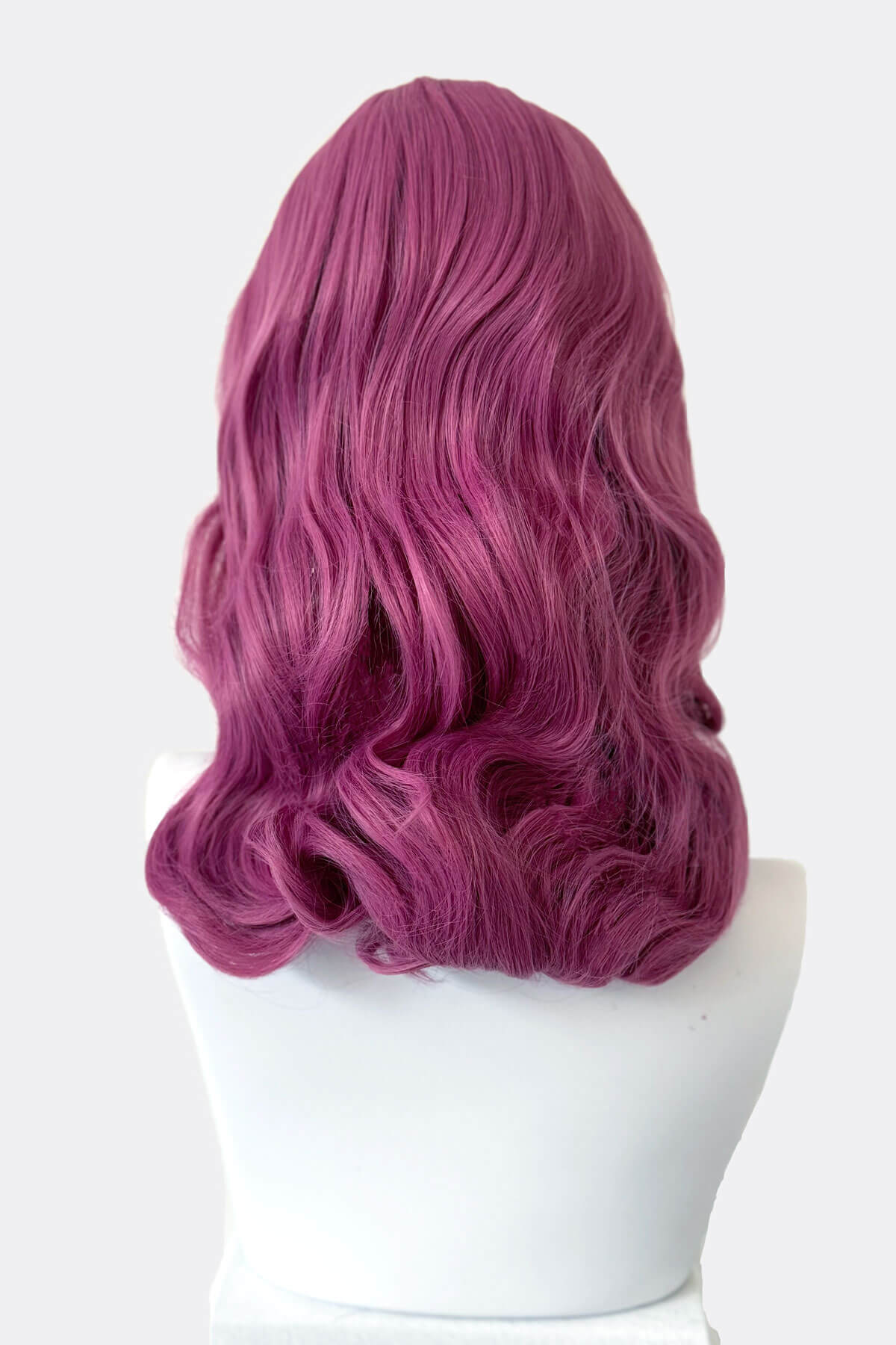 Purple wig on a white mannequin head against a white background. Pink pinup style wig, with finger waves and a short fringe, 1950s style: Stevie 2520J