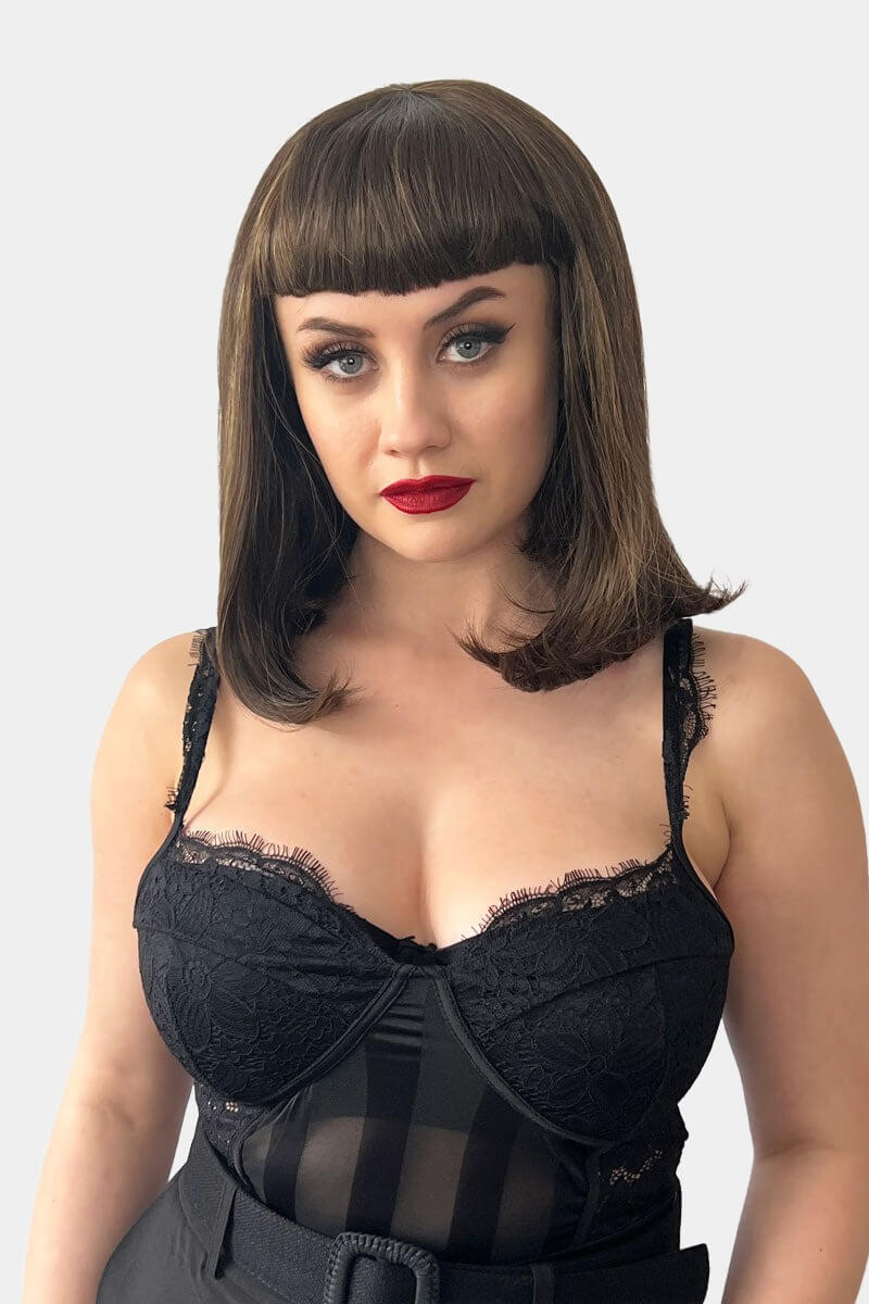 A person wearing a long bob wig with a short fringe, colored in chestnut brown with blonde highlights, styled with the hair falling just to the shoulders. Long bob wig with a short fringe, brown with blonde highlights: Jill