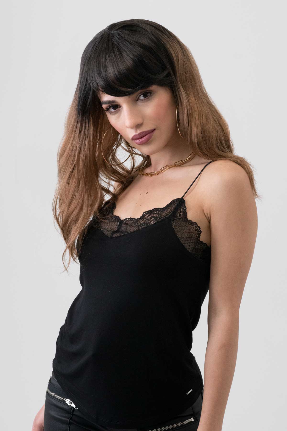 Woman wearing a black lace-trimmed top against a plain background. Long wavy bob wig (lob), dark brown to light brown ombre: Rowena