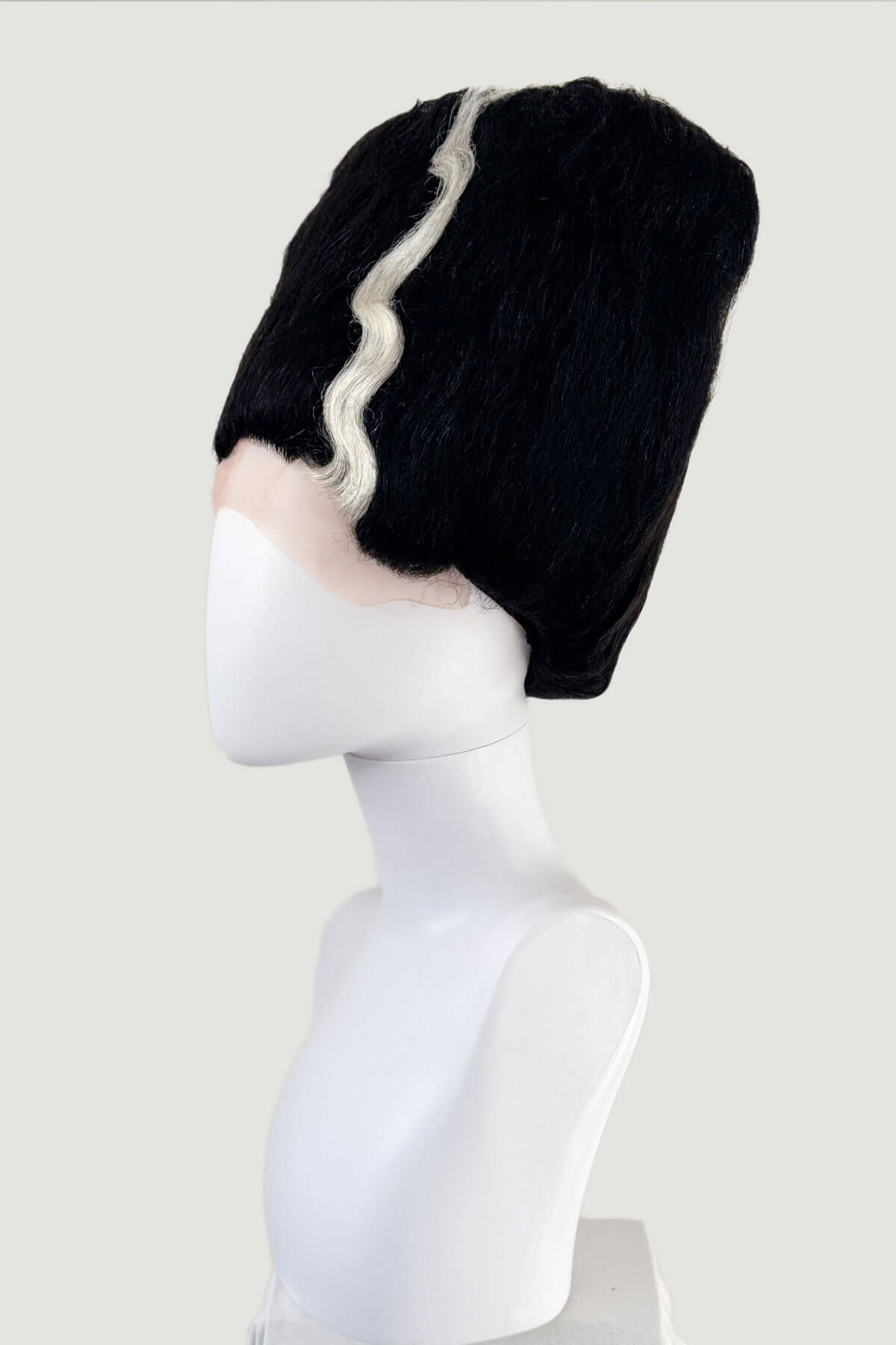 Black wig with white hairline on a mannequin head against a white background. Black wig with white fringe on a mannequin head against a white background. Bride of Frankenstein lacefront wig, black with platinum streaks: Eva