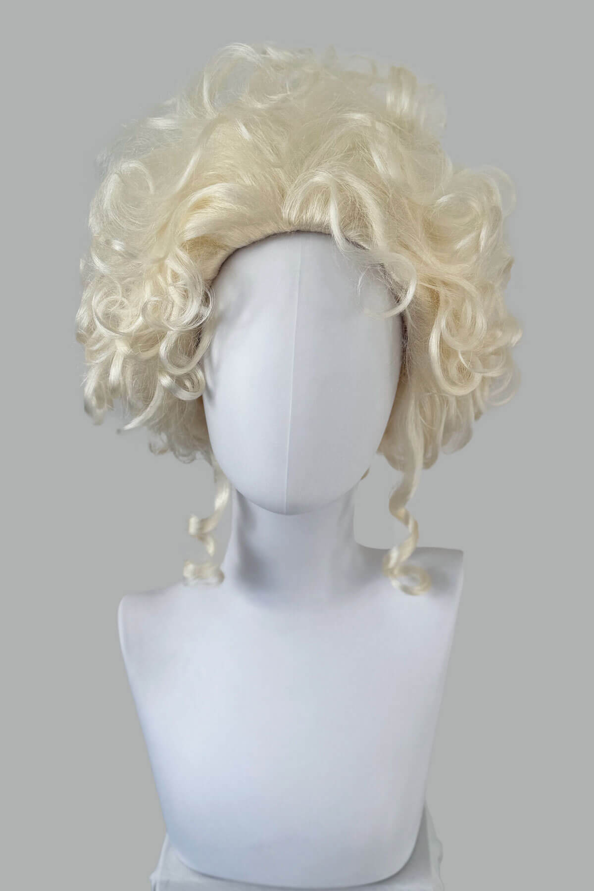 Blonde wig on a mannequin head against a gray background. Platinum blonde Marie Antoinette style wig: Marie platinum blonde 1001