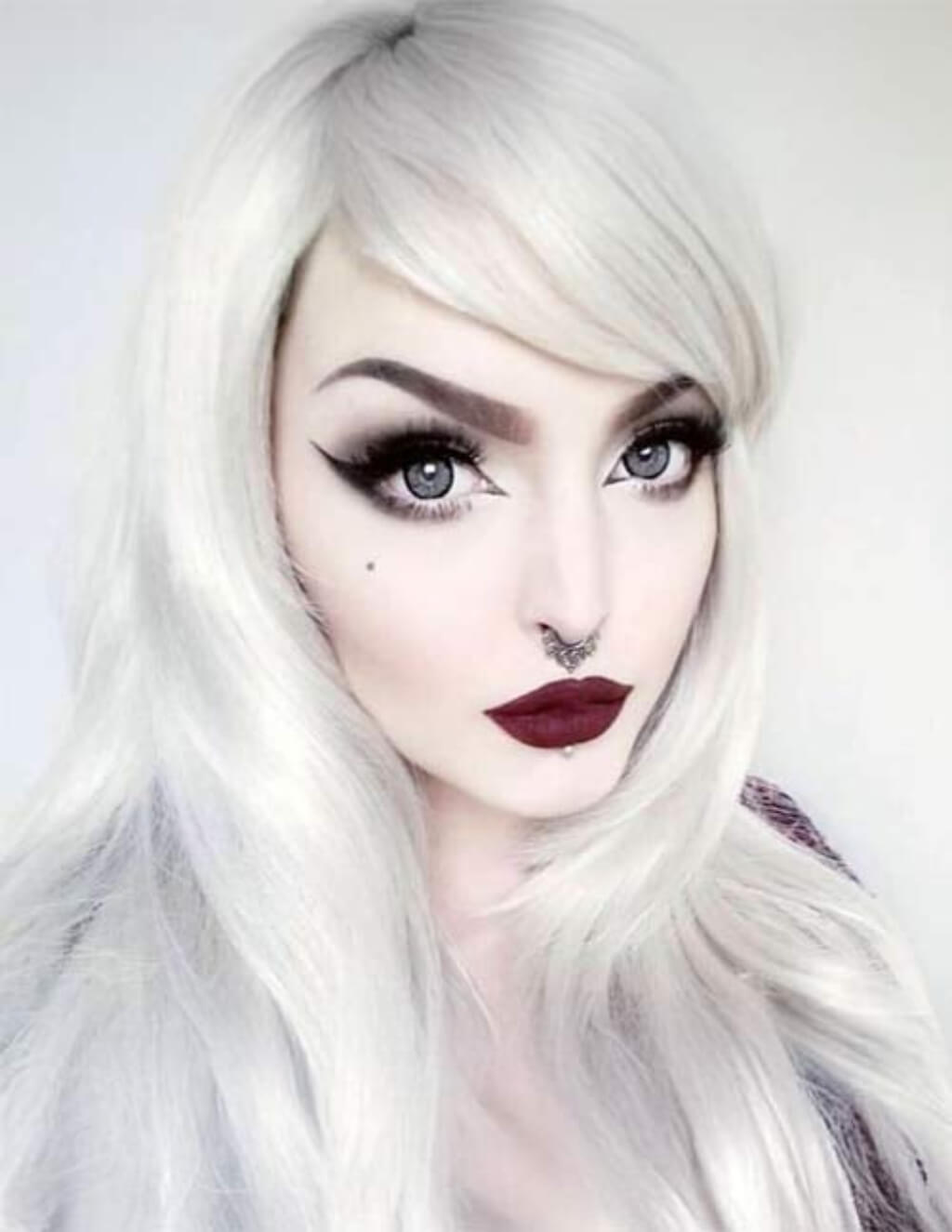 Person with long white hair and dark lipstick against a light background. Long silver/grey wig in razor cut, face framing style: London