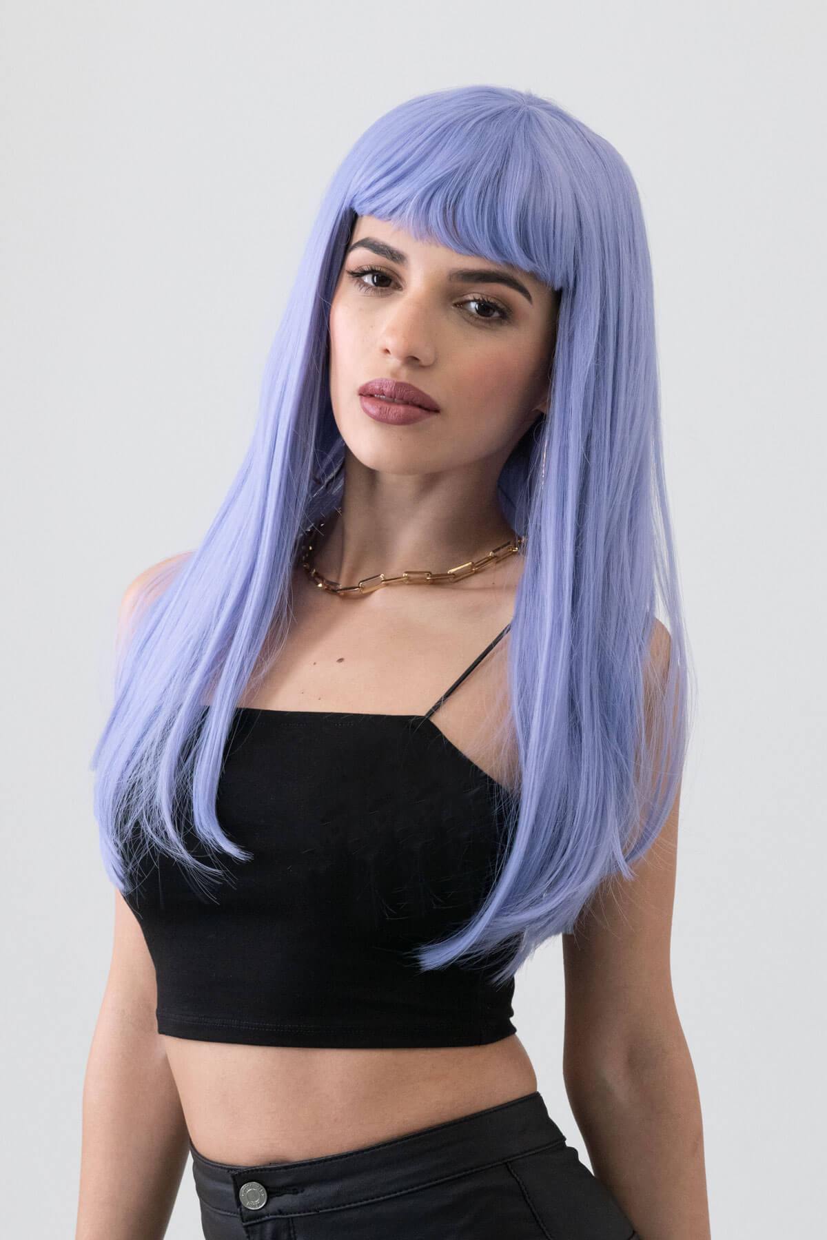 Woman with a light blue wig wearing a black top against a plain background. Long blue wig with short, straight fringe: Alyssa