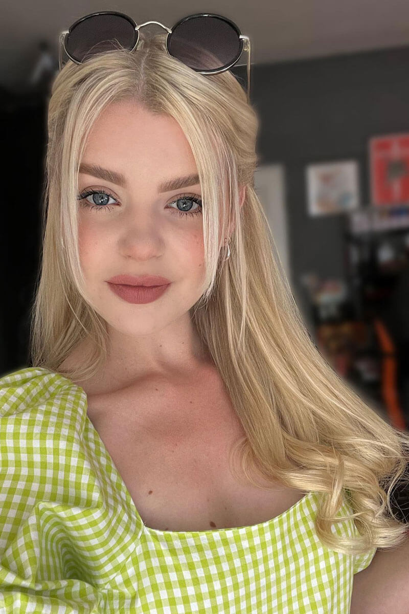A woman with long blonde hair wearing a green checkered top and sunglasses on her head. Human Hair Extensions, remy hair